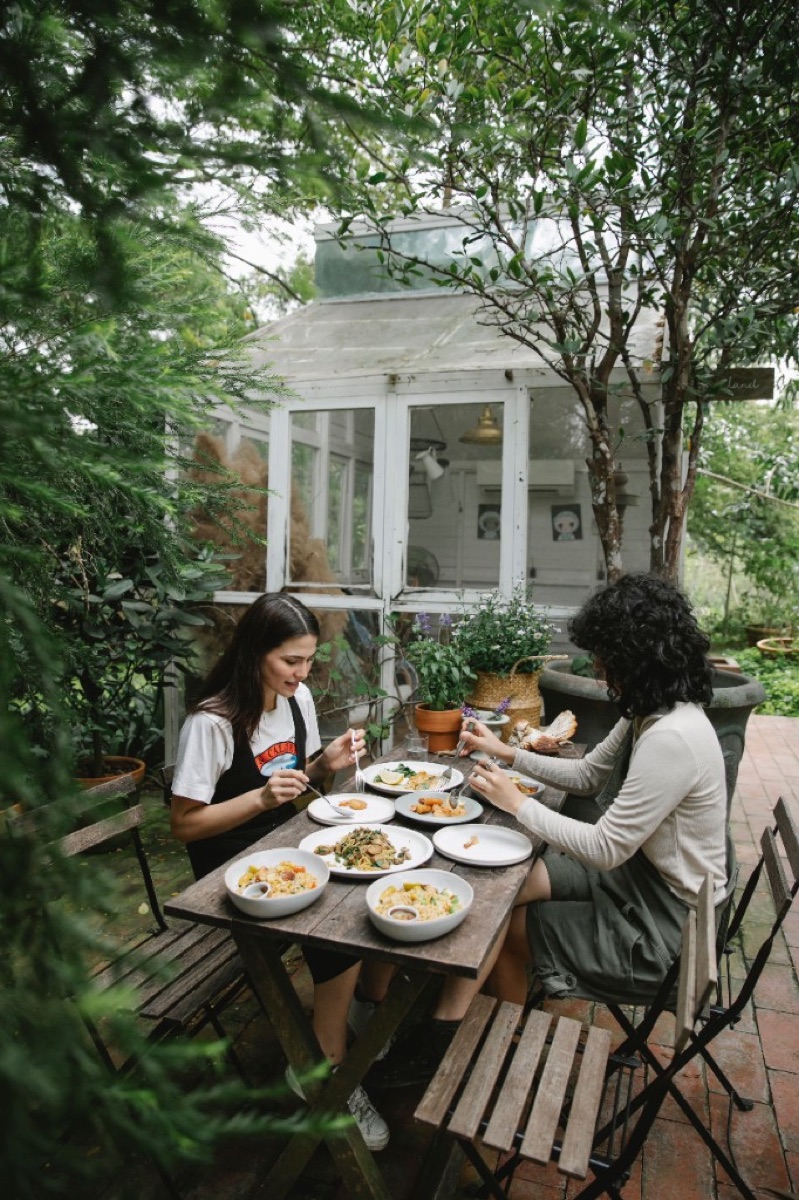 Two friends sharing food at a garden cafe