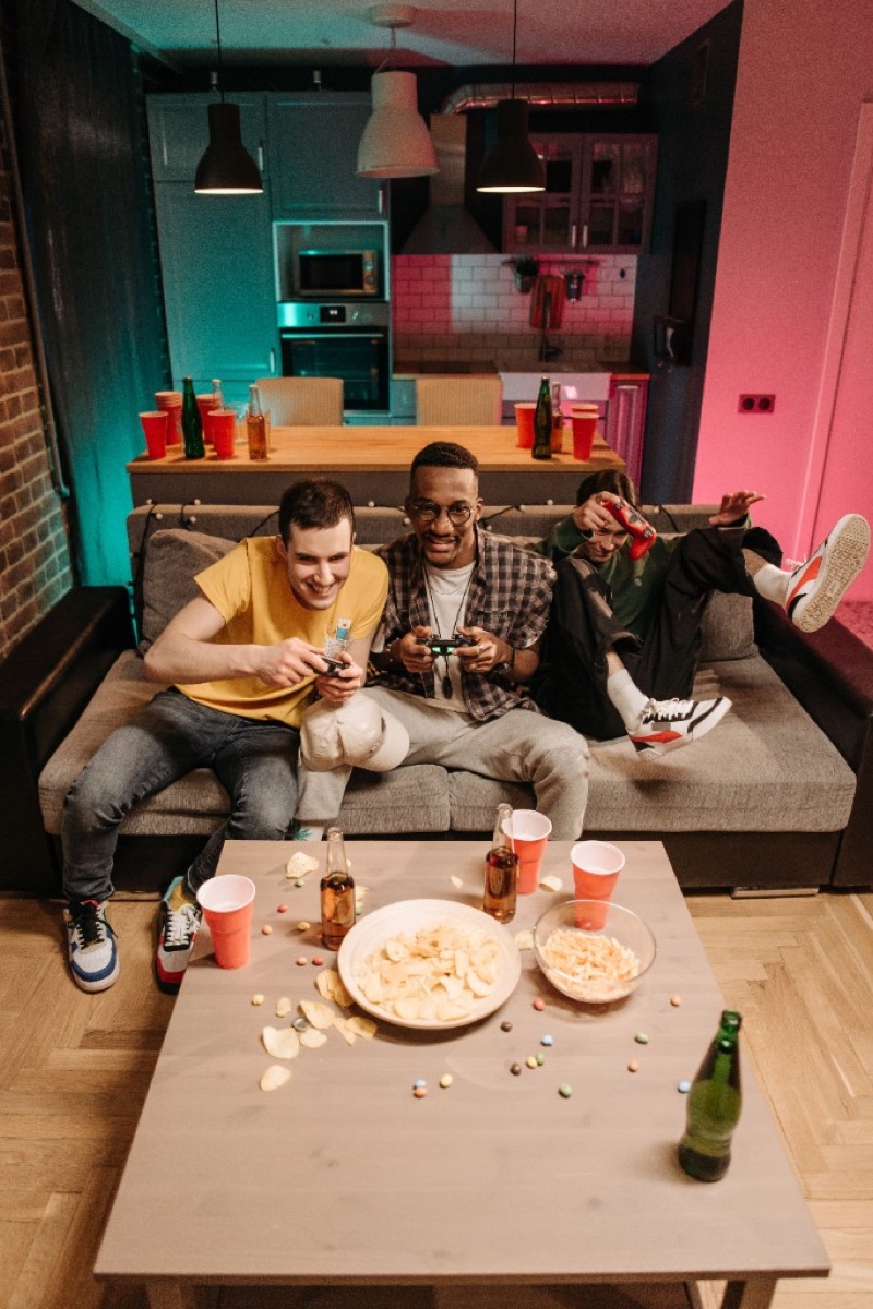 Friends playing video games together on a couch